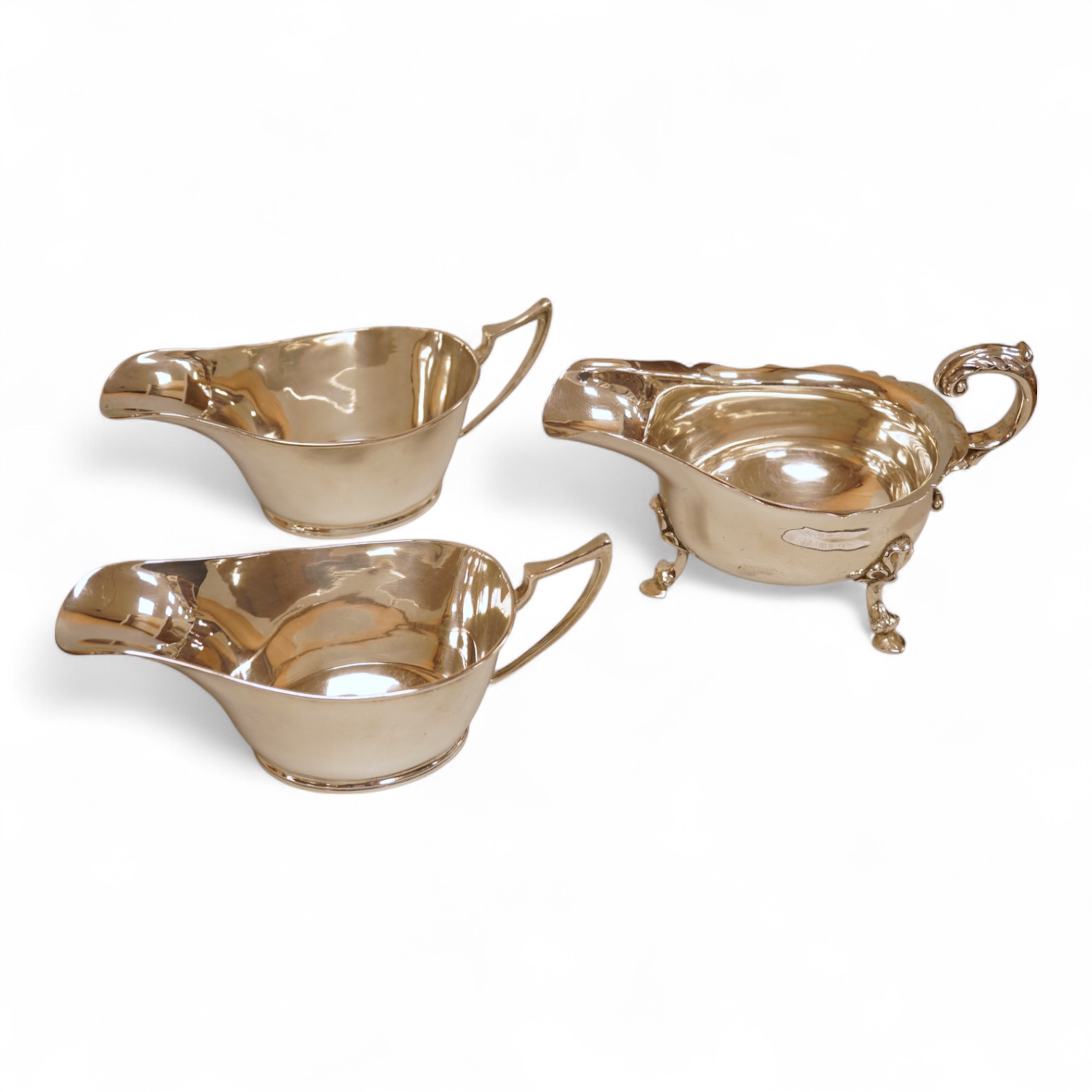A pair of George V silver sauceboats by Walker & Hall, Sheffield, 1929/30, length 17.9cm together with a George V silver sauceboat with flying scroll handle, William Comyns & Sons Ltd, London 1926, 16.4oz.